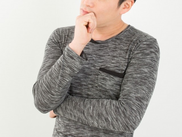 顔に手を当て考え込む人物